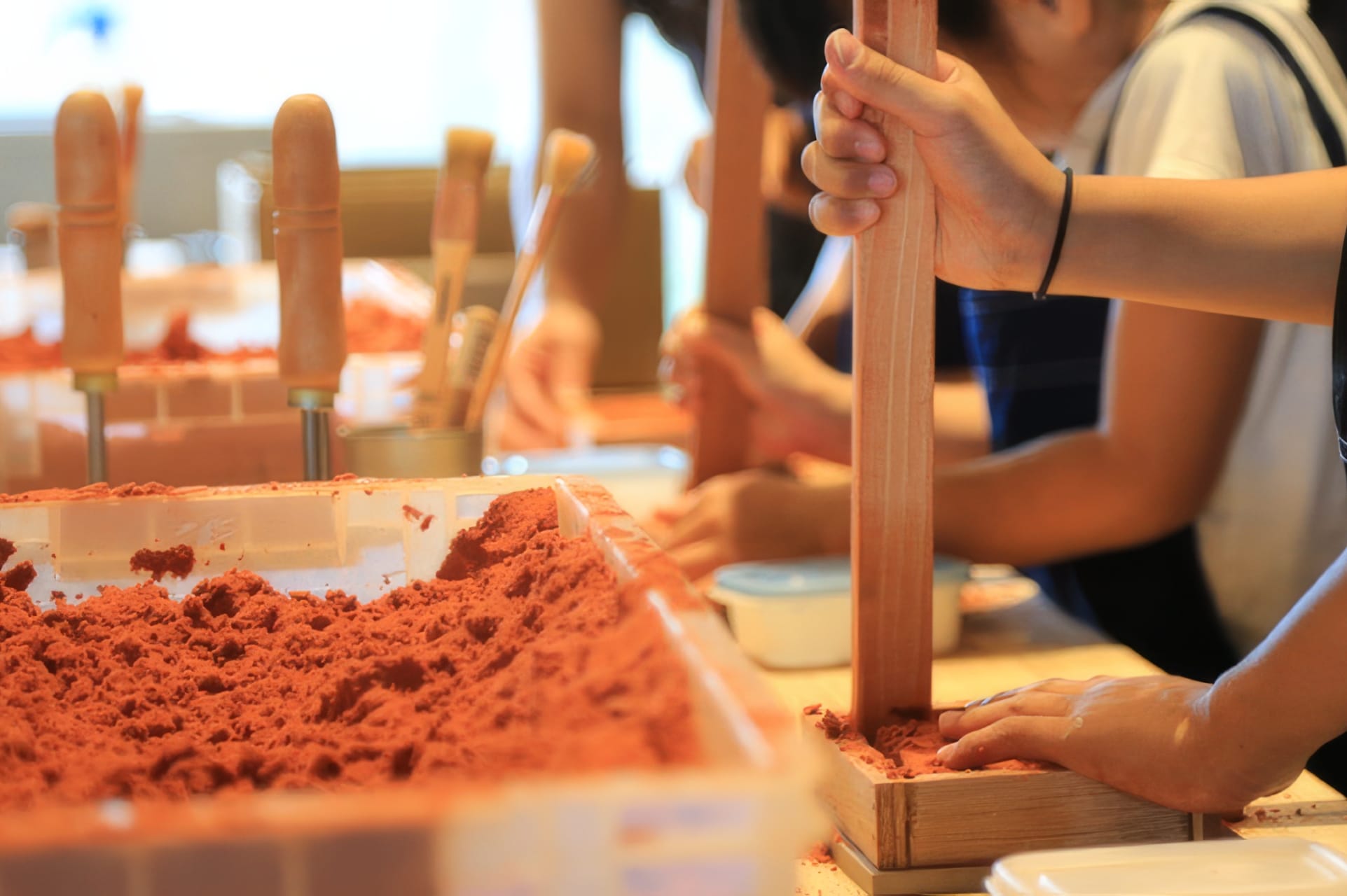 Visitors packing sand molds by hand during a casting workshop at the Nousaku factory in Takaoka, Toyama