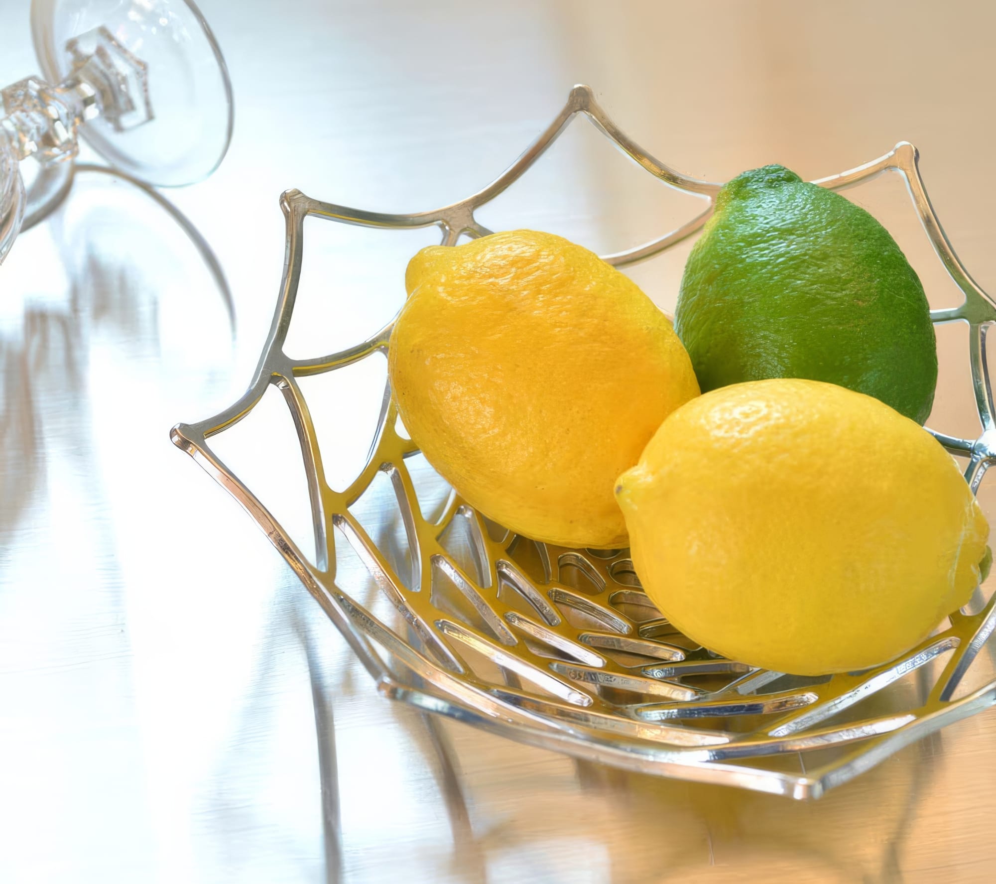 Nousaku KAGO Dahlia bendable tin basket shaped into a curved bowl and holding lemons, demonstrating the malleability of 100 percent pure tin